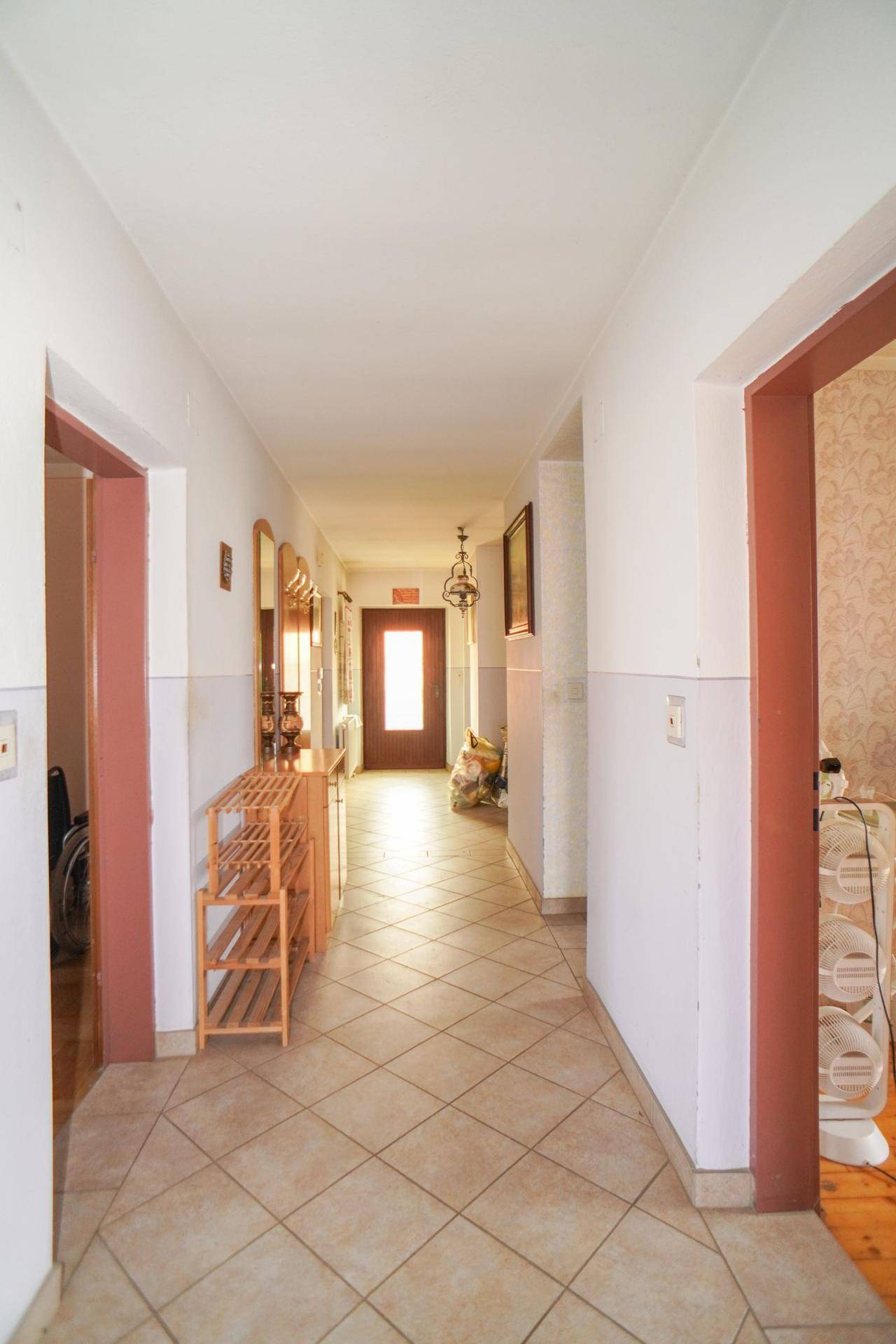 Heller Eingangsbereich mit Fliesenboden, Garderobe und Blick auf die Eingangstür.