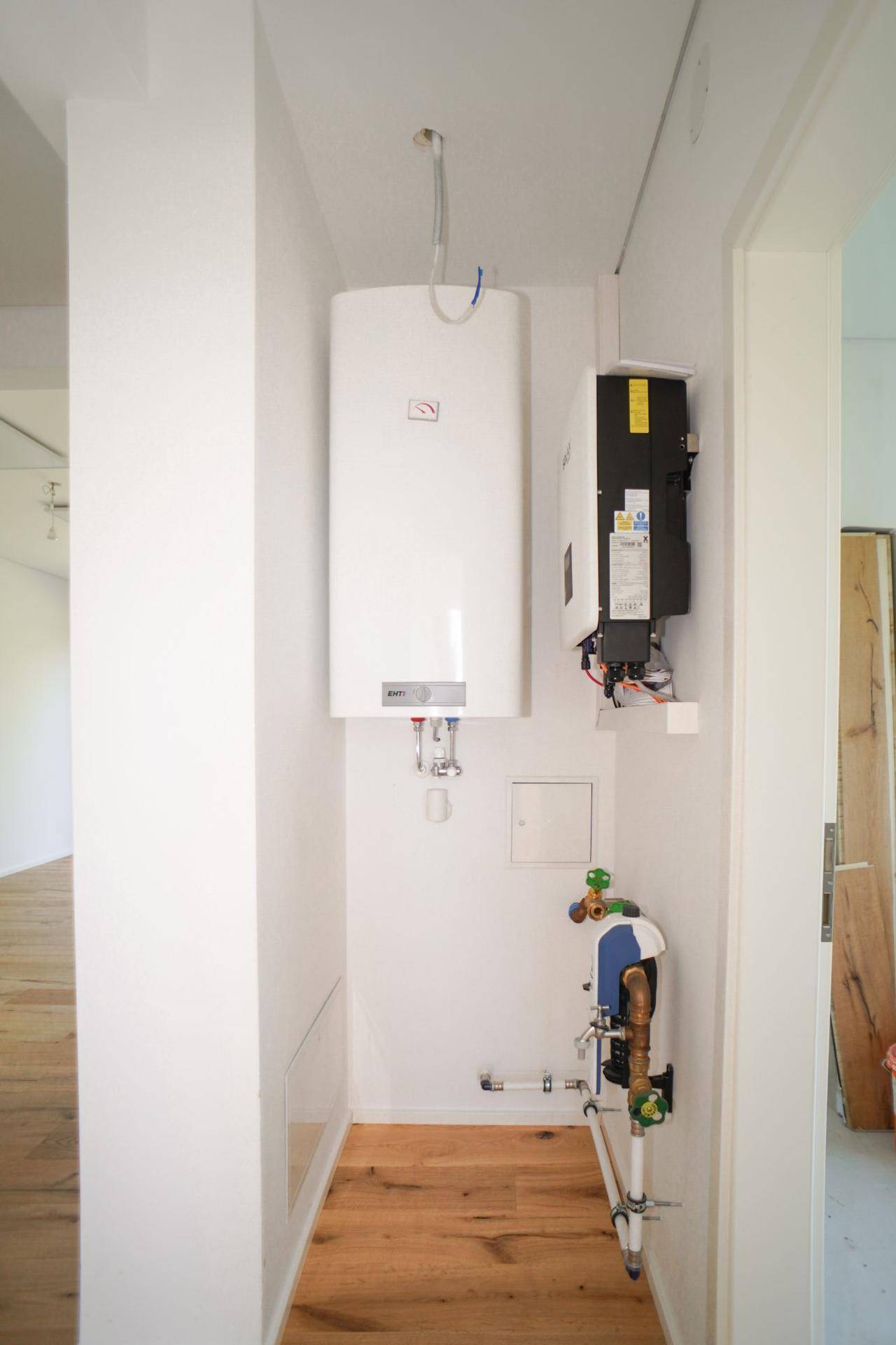 Technikraum mit Warmwasserbereiter und weiteren Installationen, bereit für den Anschluss.