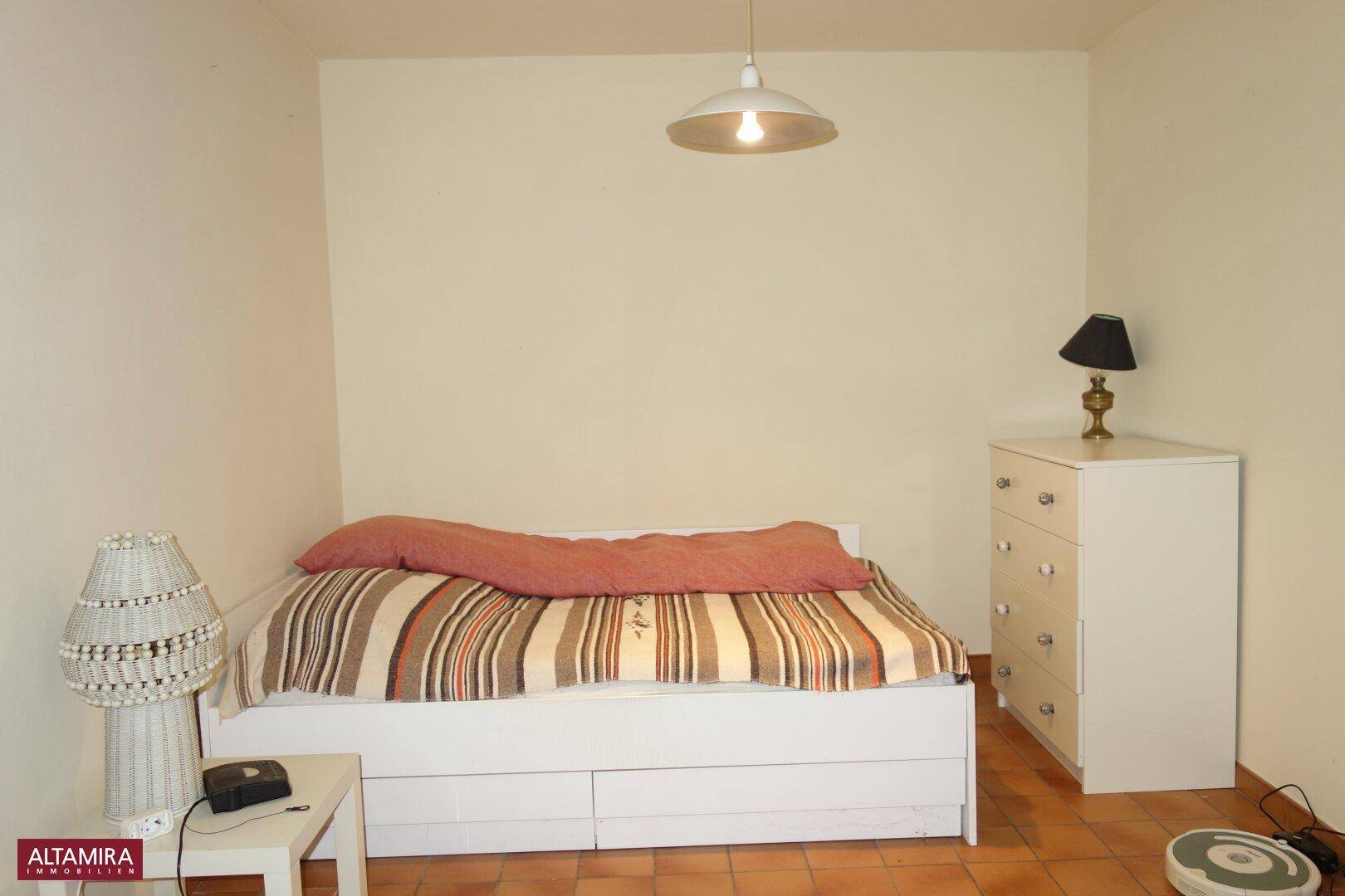Gemütliches Schlafzimmer mit Doppelbett, Kommode und Terrakottafliesen.