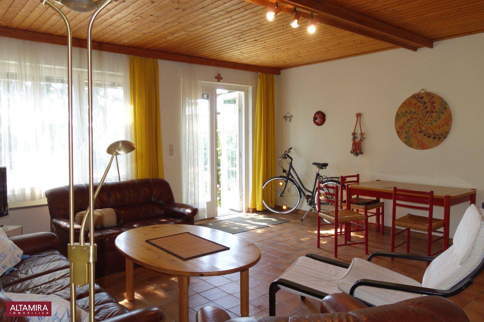 Heller Wohn-Essbereich mit Holzbalkendecke, Ledersofas und direktem Gartenzugang.