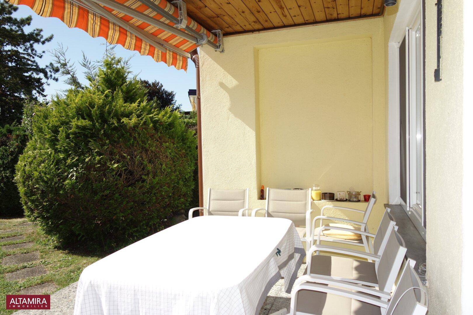 Überdachte Terrasse mit Gartenmöbeln und Blick auf den grünen Gartenbereich.
