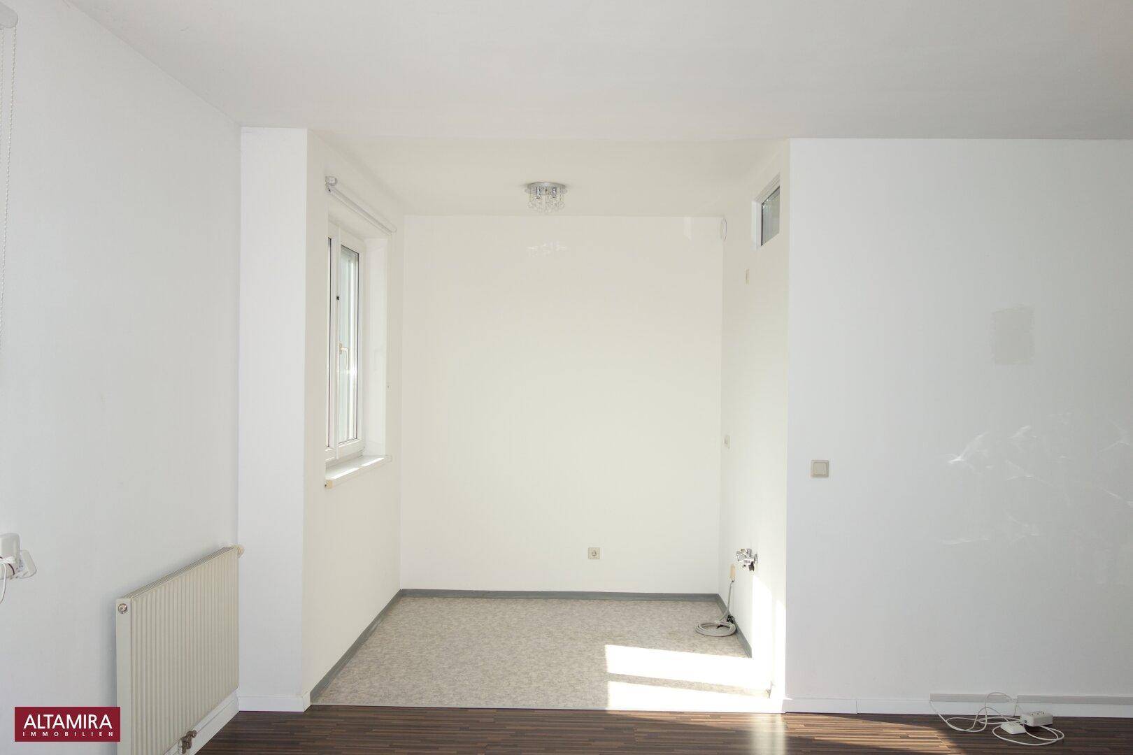 Heller Küchenbereich mit Anschlüssen für Geräte und einem Fenster, das Tageslicht spendet.
