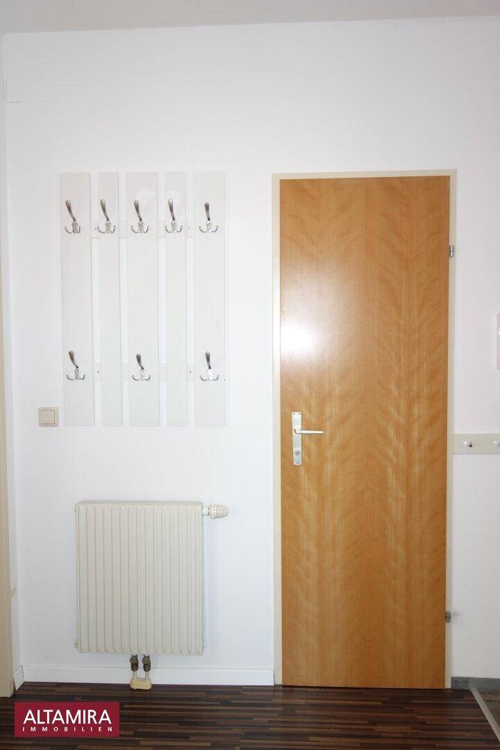 Heller Flur mit Garderobe und Holztür, der einen praktischen Empfangsbereich bietet.