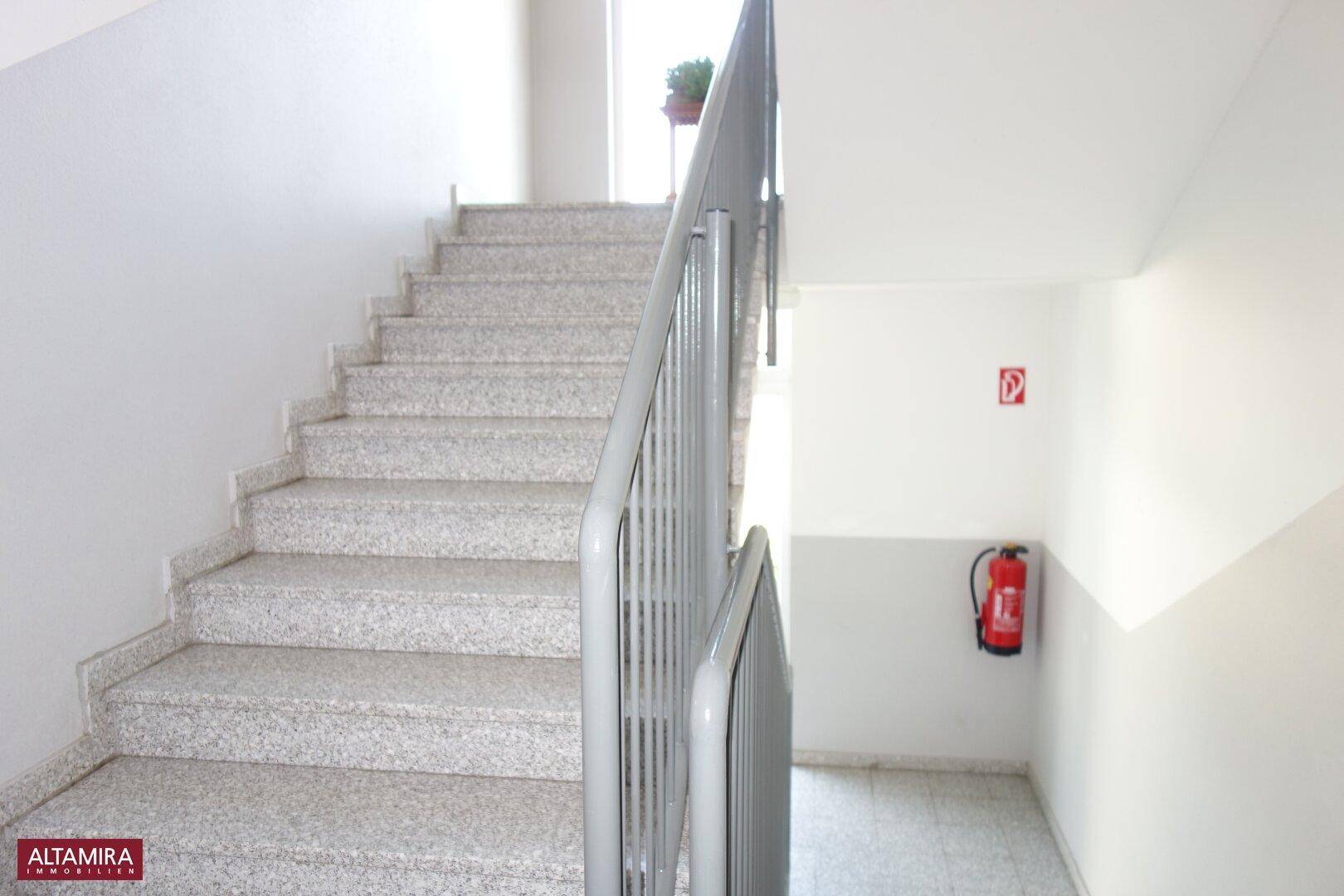 Treppenhaus mit Granitstufen und Metallgeländer, das die verschiedenen Etagen verbindet.