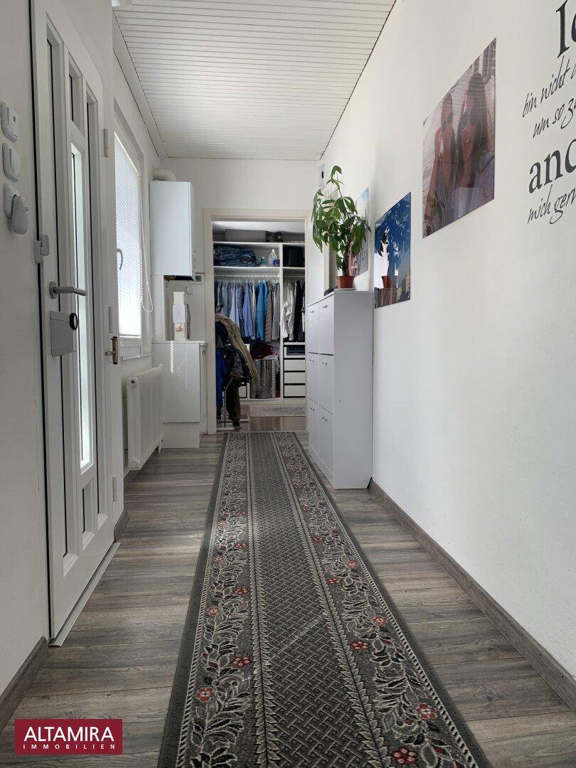 Langer Flur mit Holzboden, weiß gestrichenen Wänden und Zugang zu einem begehbaren Kleiderschrank.