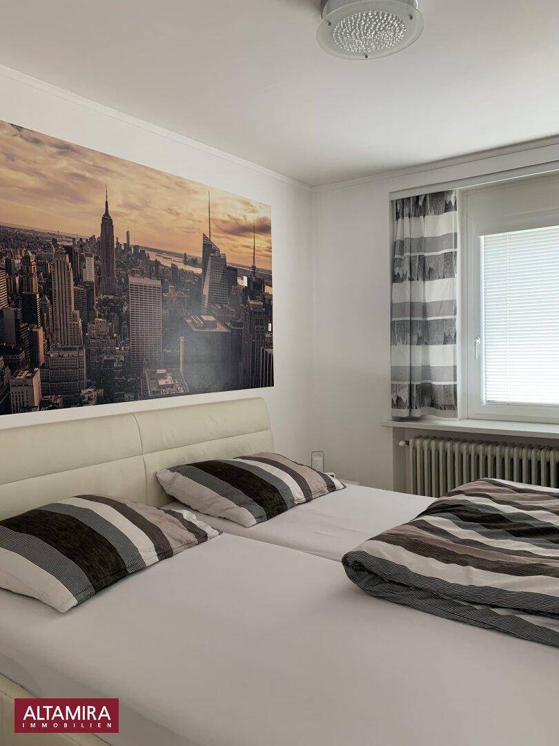 Schlafzimmer mit Doppelbett, einer großen Wandtapete der New Yorker Skyline und einem Fenster.