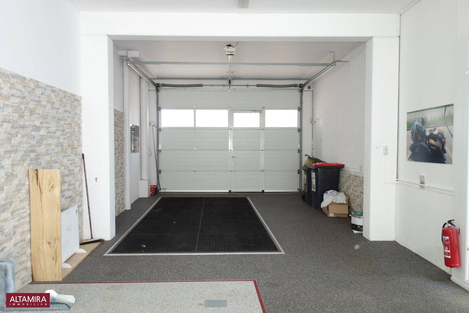 Geräumige Garage mit einem großen Rolltor, Steinwandakzenten und einem Teppichboden.