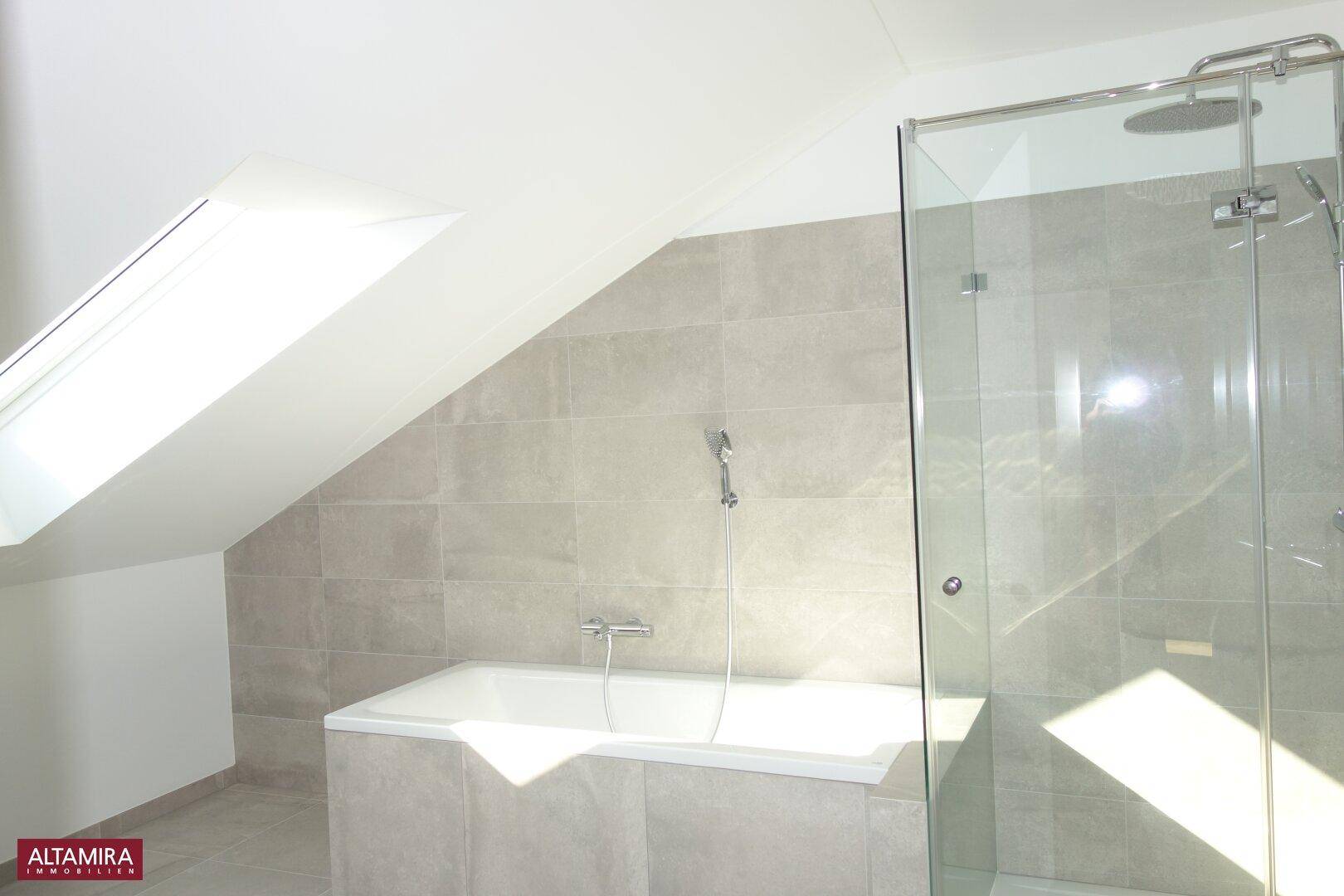 Modernes Badezimmer mit Badewanne, begehbarer Dusche und Dachfenster unter einer Dachschräge.