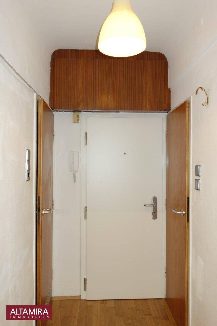 Eingangsbereich mit Holzboden, weißer Tür und praktischen Oberschränken.