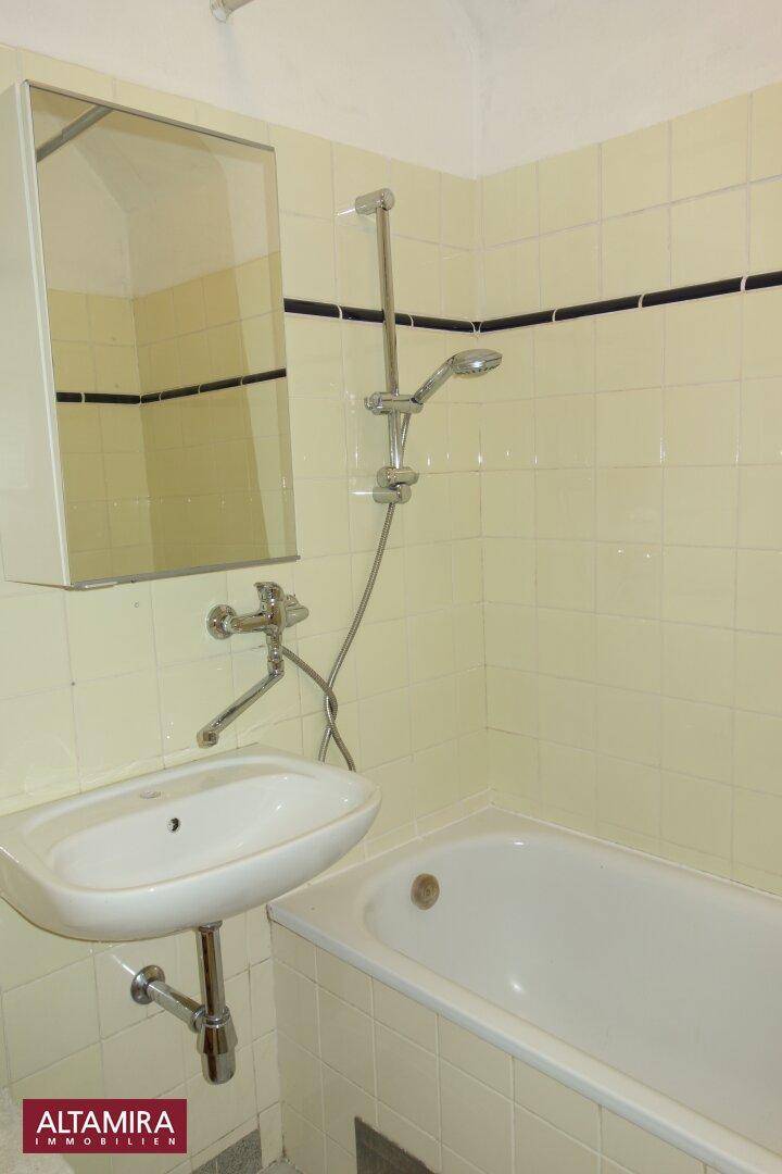 Badezimmer mit Badewanne, Waschbecken und hellgelben Fliesen im 80er-Jahre-Stil.