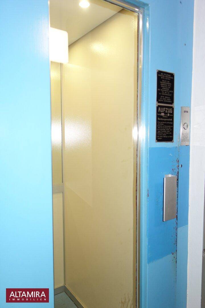 Aufzug in einem Gebäude mit blauer Tür und Bedienfeld.