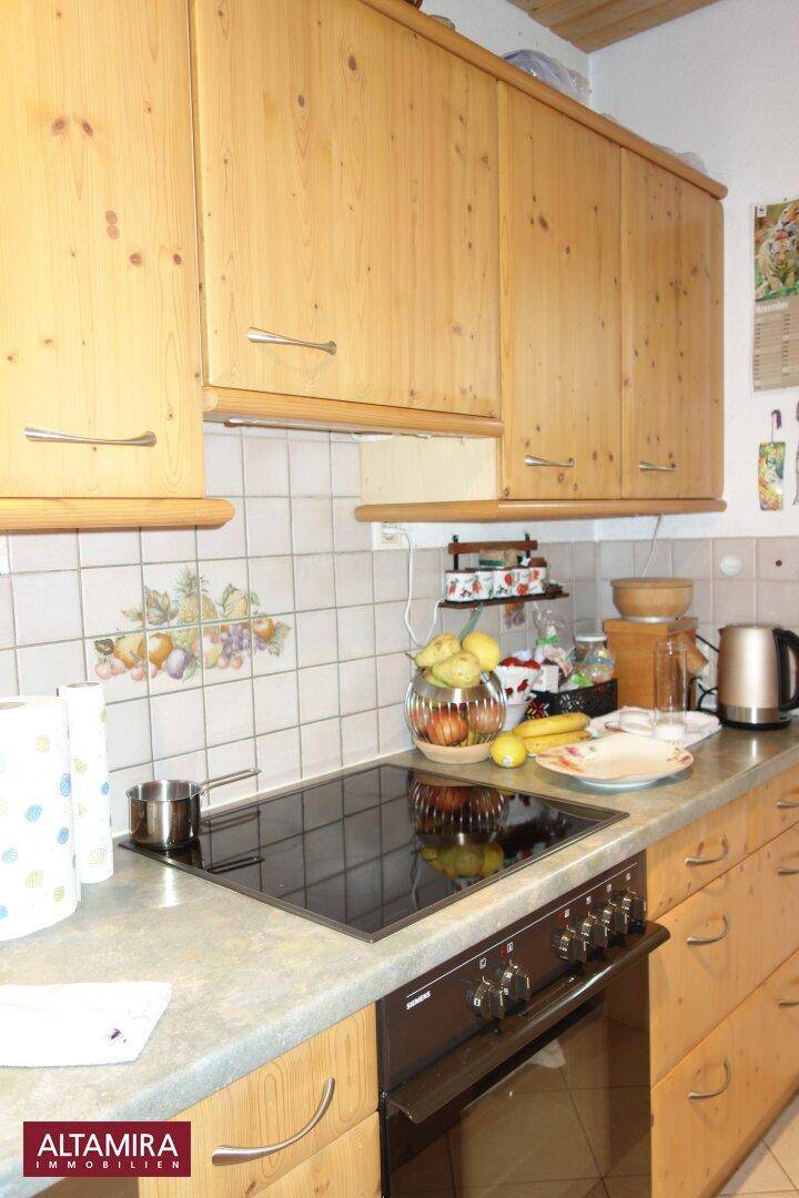 Detailansicht der Küche mit Induktionskochfeld, Backofen und gefliestem Spritzschutz.