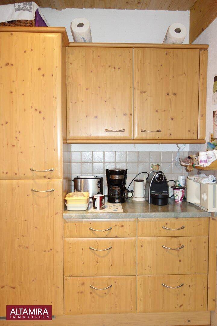 Küchenzeile mit Holzschränken, Arbeitsplatte und Platz für Kaffeemaschine und Toaster.