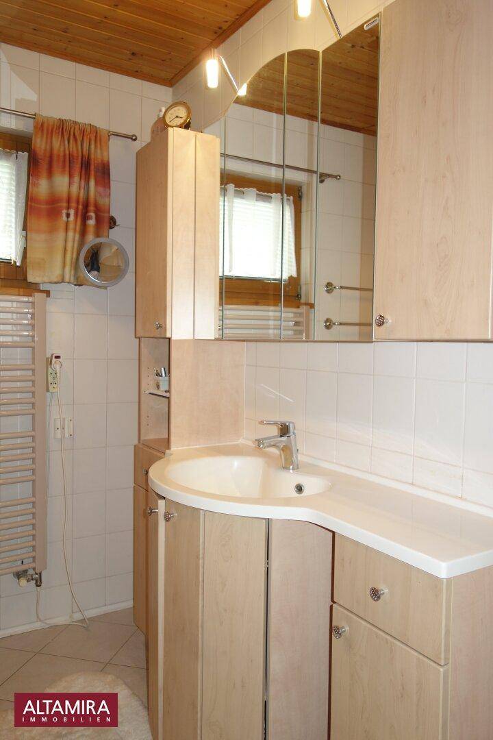Badezimmer mit Waschtisch, Spiegelschrank, Fenster und beheiztem Handtuchhalter.