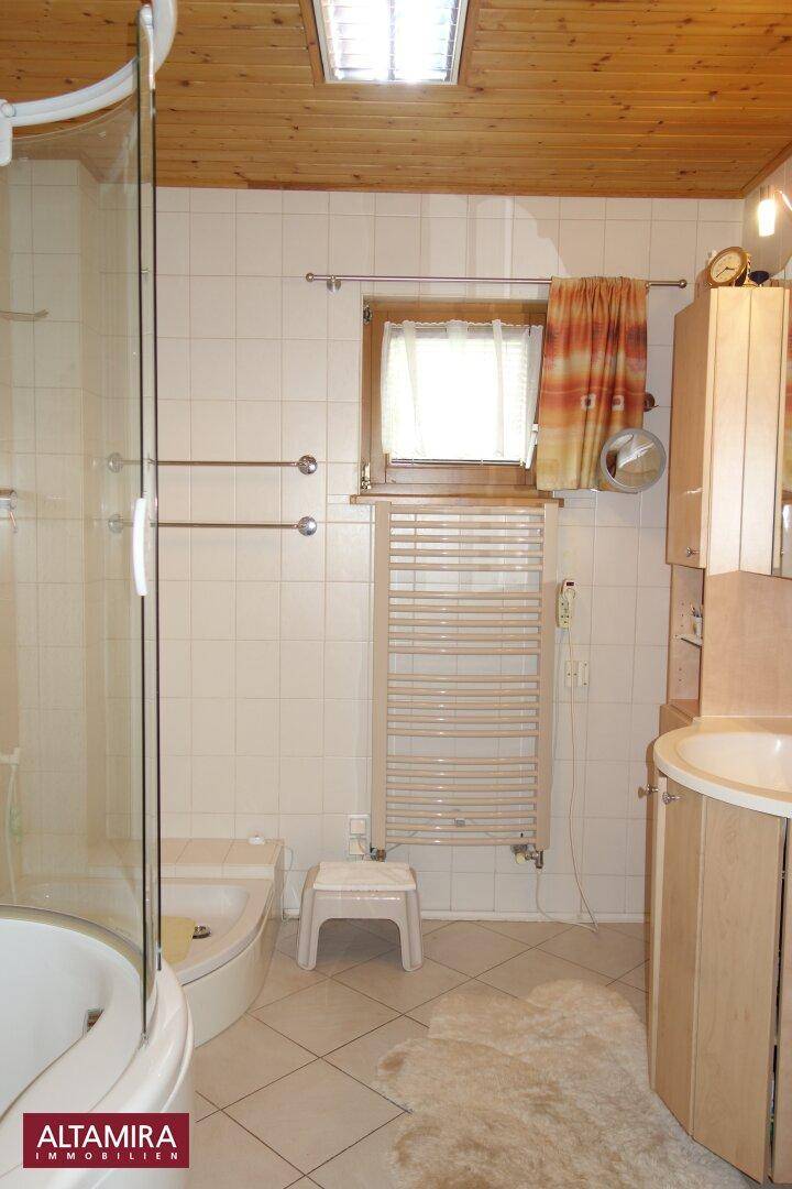 Helles Badezimmer mit Eckbadewanne, Dusche, WC, Waschtisch und beheiztem Handtuchhalter.