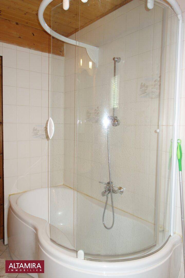 Helles Badezimmer mit Eckbadewanne, Duschabtrennung und Holzdecke, hell gefliest.