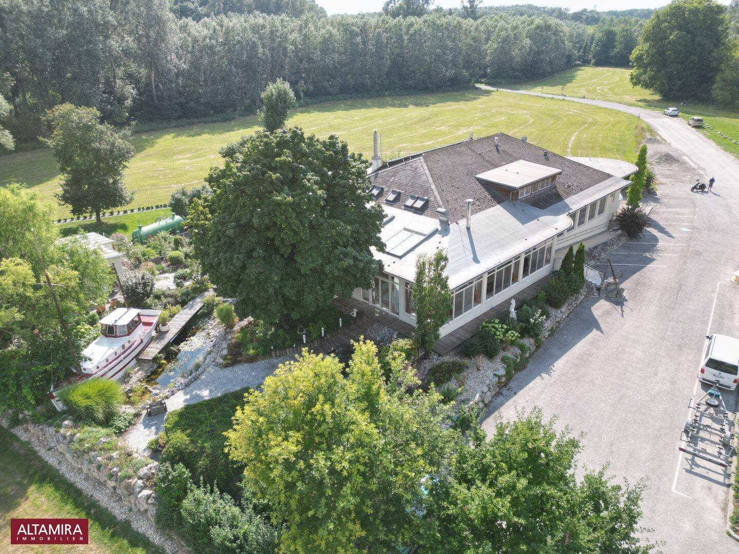 Luftaufnahme des Anwesens mit Hauptgebäude, weitläufigem Garten und umliegender Natur.