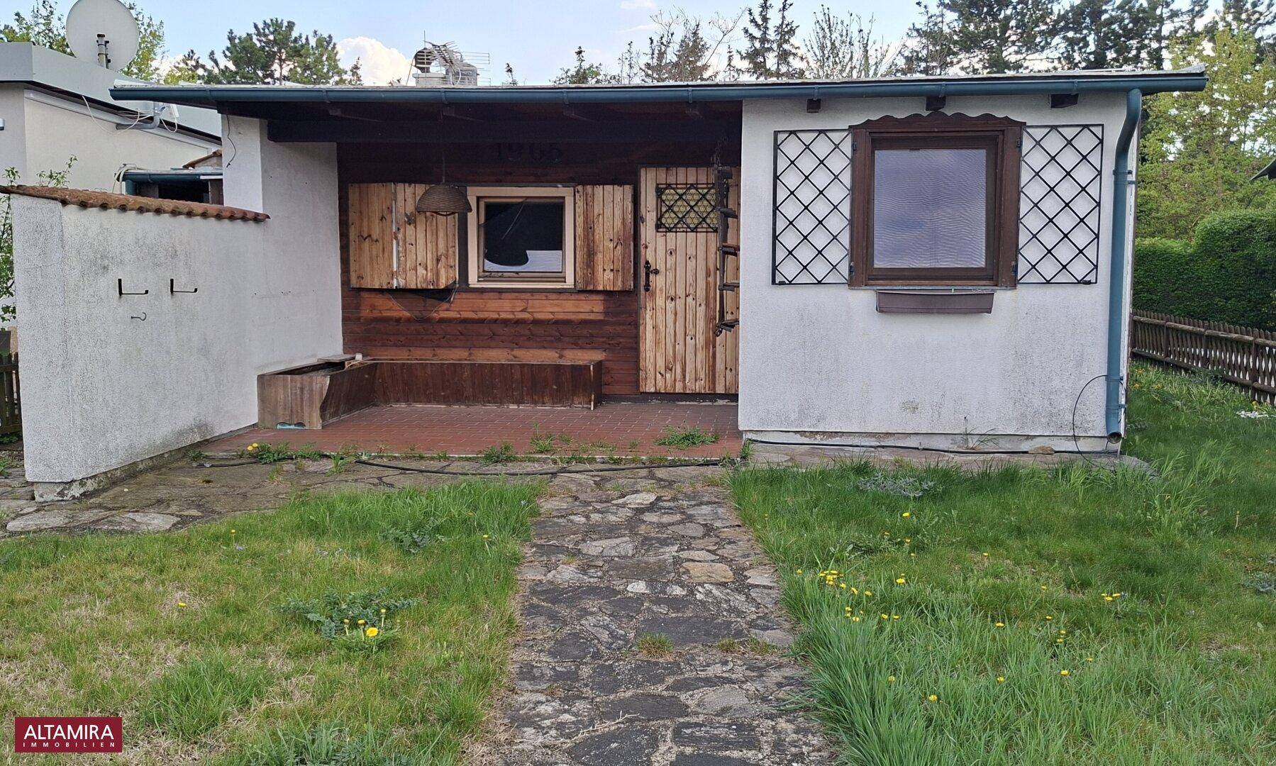 Kleines Haus mit Gartenweg und Rasenfläche, umgeben von einer ländlichen Atmosphäre.