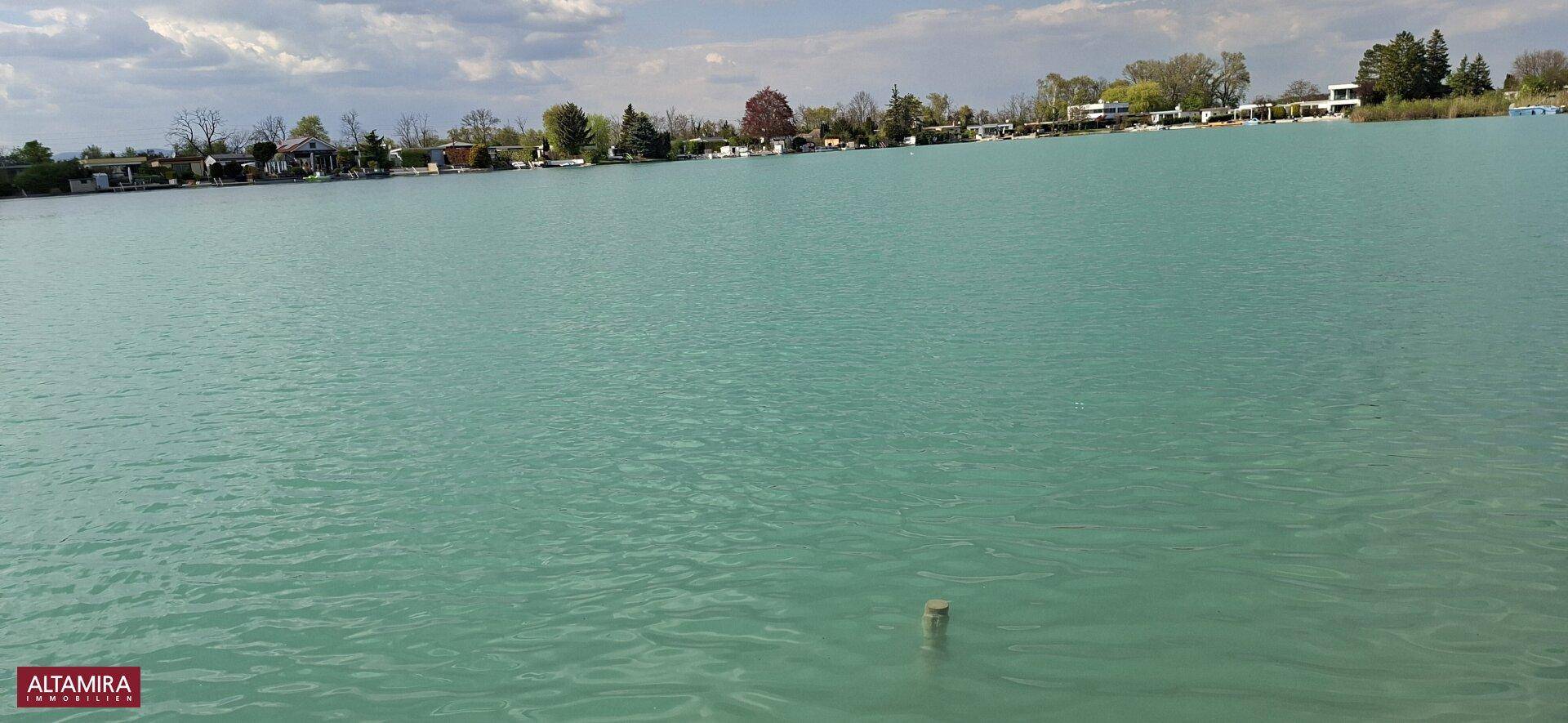 Weitläufige Ansicht des ruhigen Sees unter einem leicht bewölkten Himmel.
