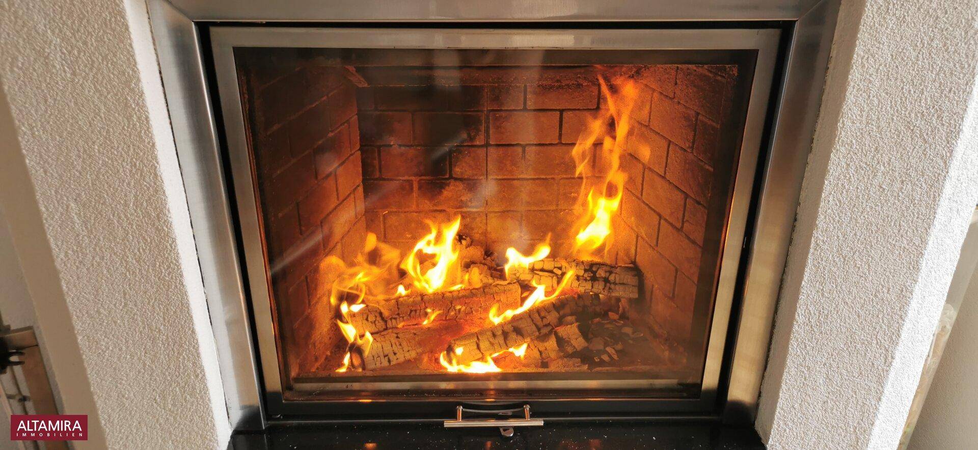 Gemütlicher Kamin mit brennendem Feuer, der eine warme Atmosphäre im Wohnbereich schafft.