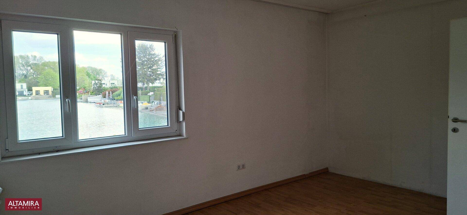 Helles Schlafzimmer mit Holzboden und großem Fenster mit direktem Seeblick.