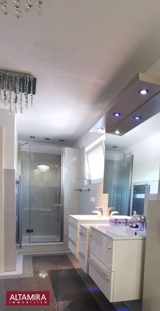 Geräumiges Badezimmer mit Doppelwaschbecken, großer Duschkabine und moderner Beleuchtung.