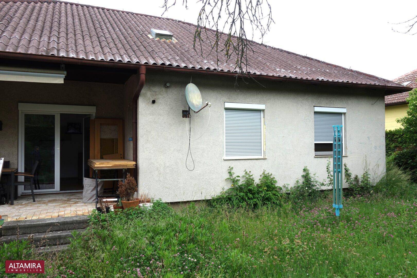 Rückseite des Hauses mit Gartenbereich, Rollläden an den Fenstern und Wäscheleine.