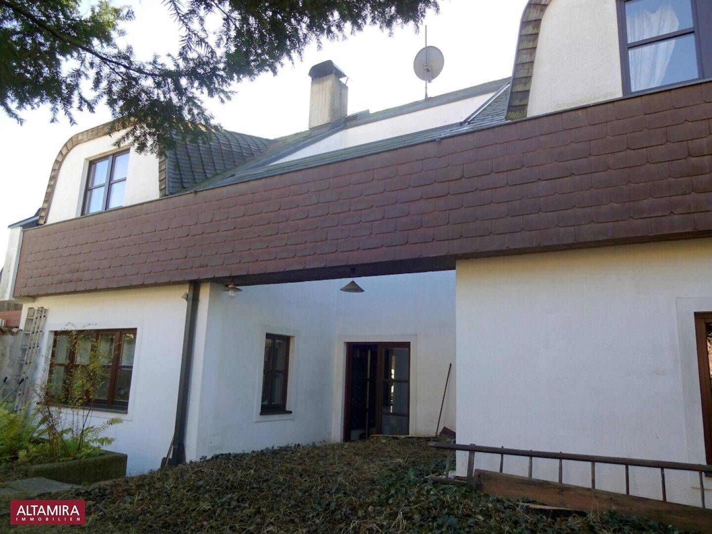 Rückseite des Hauses mit einem überdachten Bereich und einer Rampe zum Eingang.