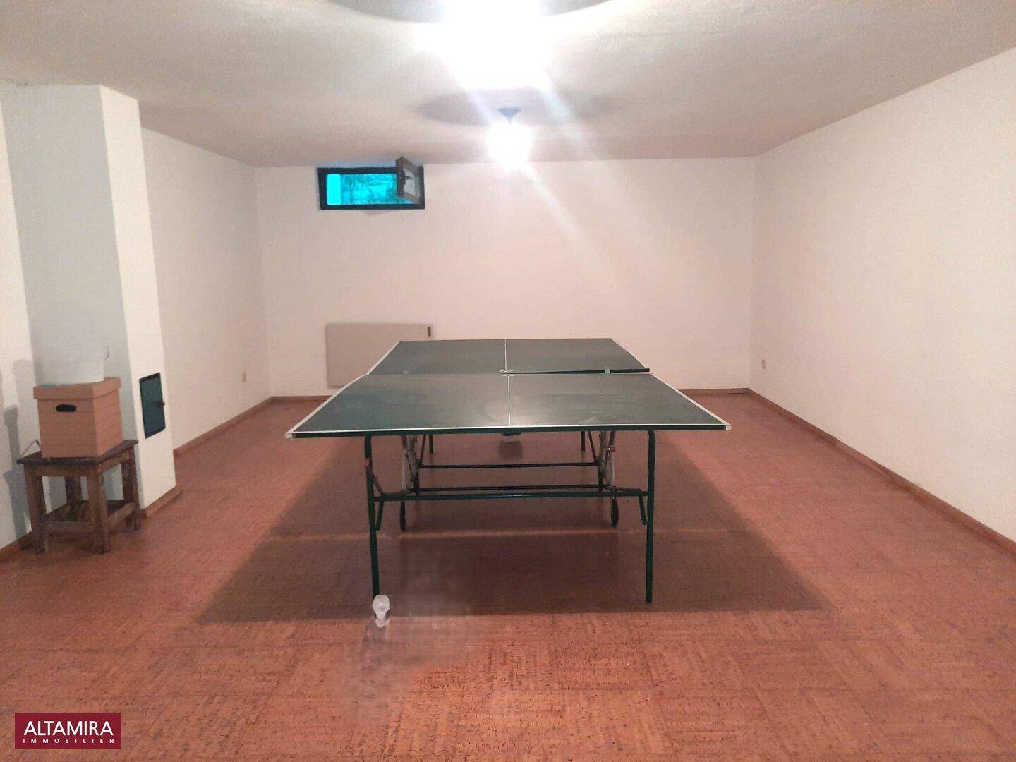 Geräumiger Kellerraum mit Tischtennisplatte, ideal für Freizeitaktivitäten.