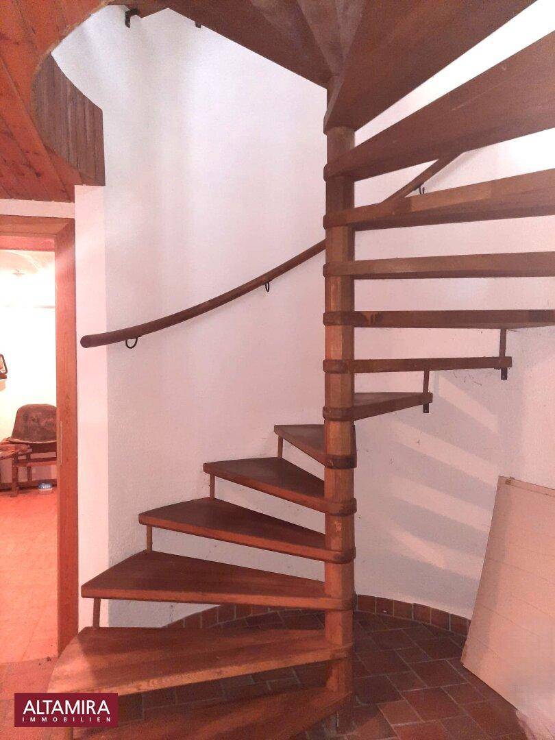 Eine elegante Holzwendeltreppe führt zu den oberen Etagen des Hauses.