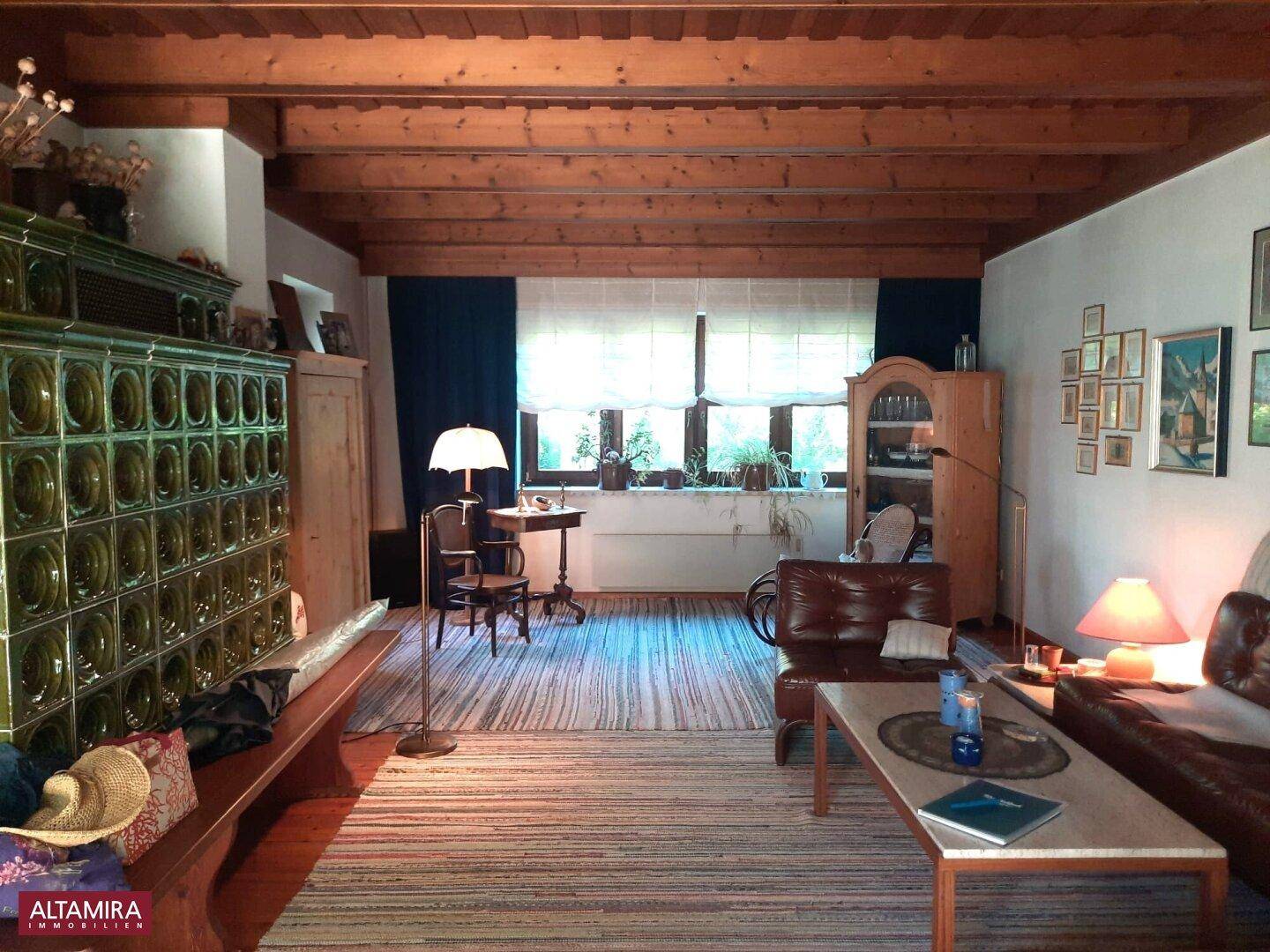 Wohnzimmer mit traditionellem Kachelofen, Holzbalkendecke und gemütlicher Einrichtung.