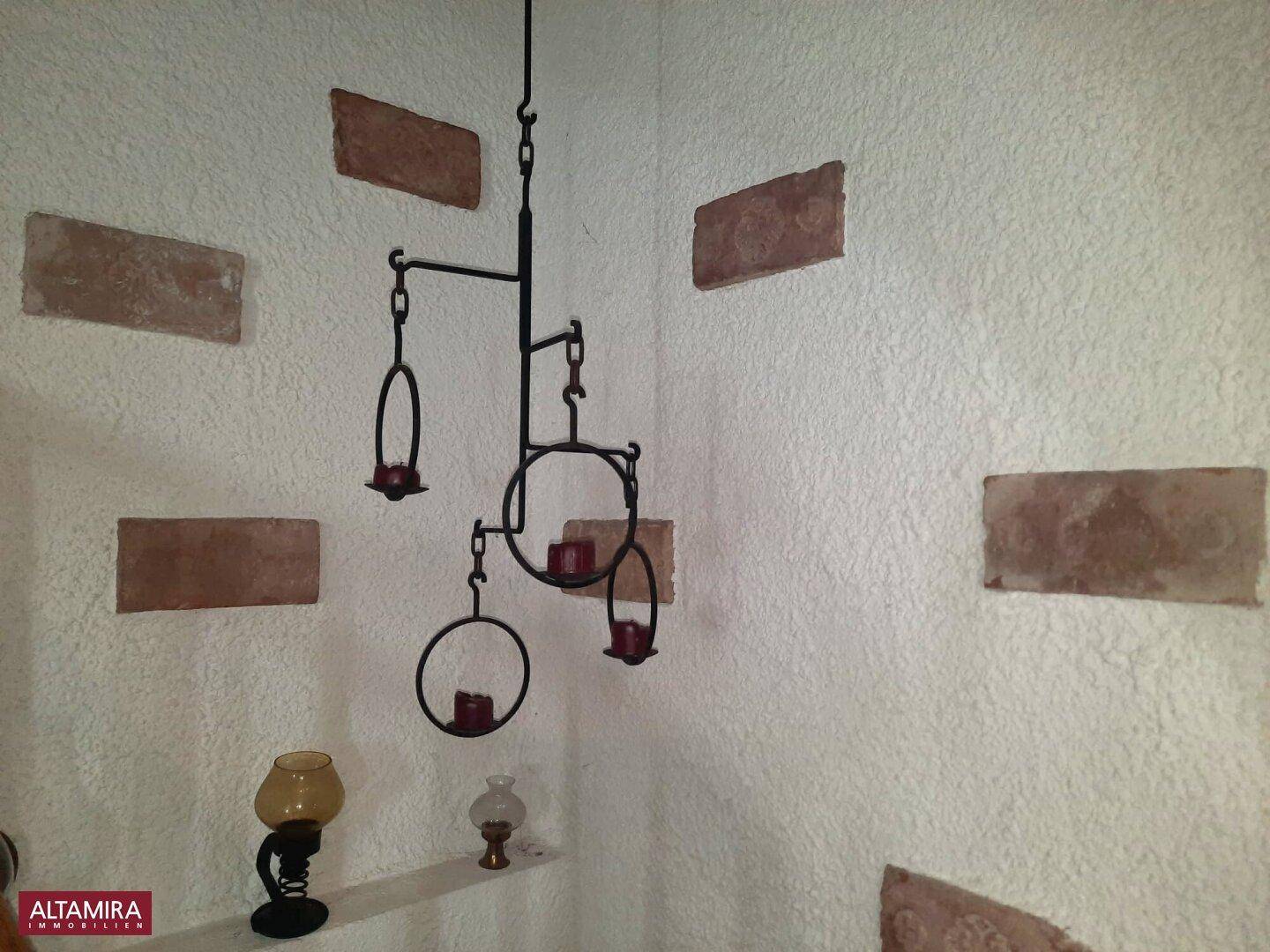 Detailaufnahme einer Wanddekoration mit schmiedeeisernem Kerzenhalter und Ziegelakzenten.