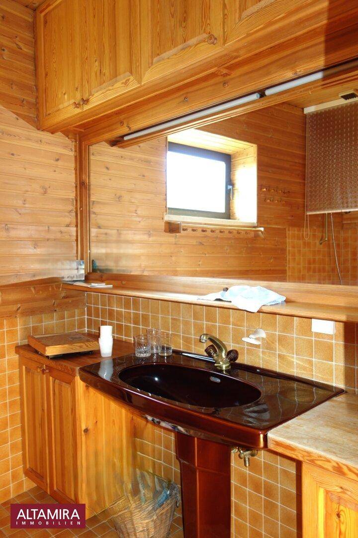 Rustikales Badezimmer mit Holzverkleidung, braunem Waschbecken und kleinen Fliesen.