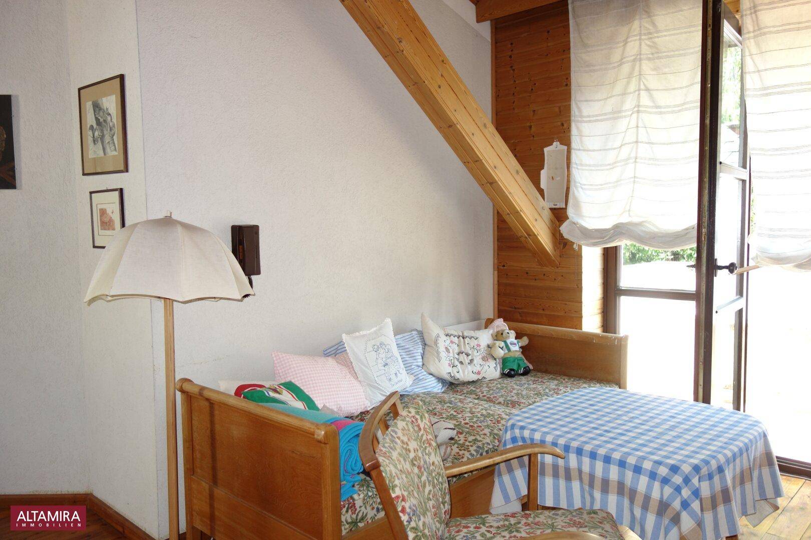 Gemütliches Schlafzimmer im Dachgeschoss mit Holzbalken, Einzelbett und Zugang zum Balkon.