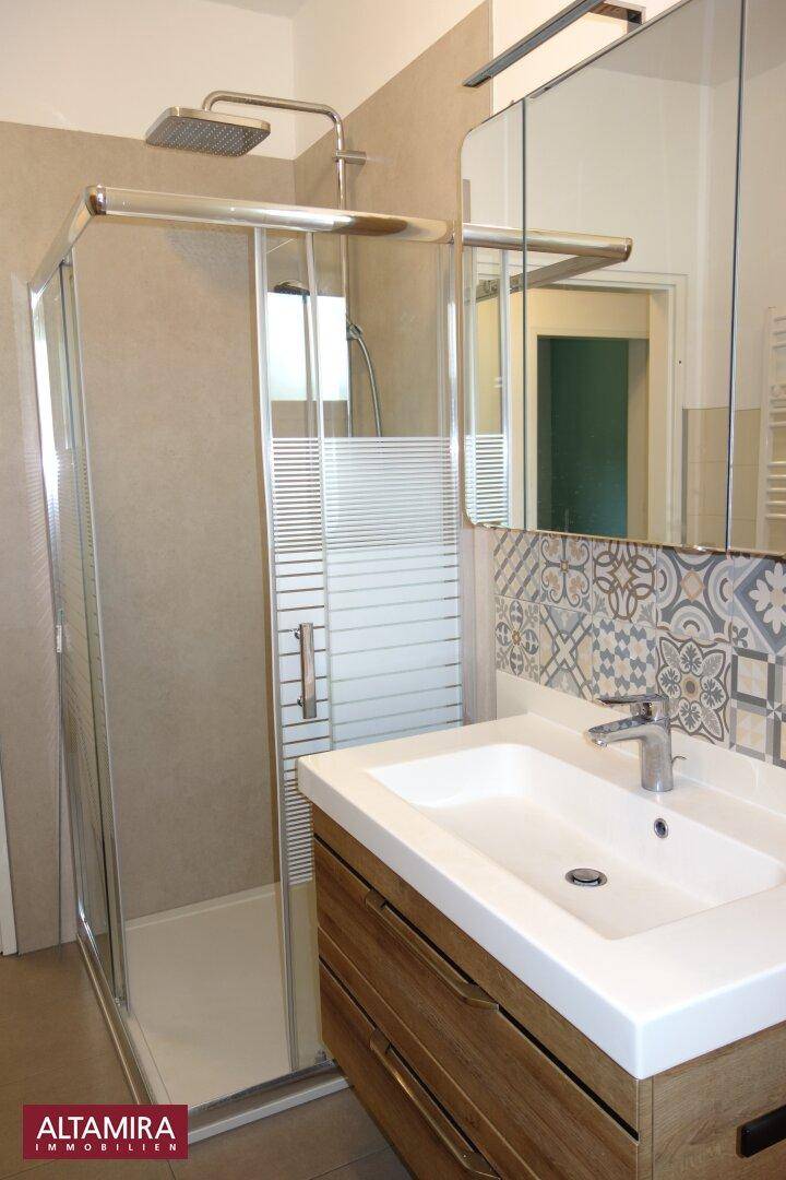 Modernes Badezimmer mit begehbarer Dusche, Einzelwaschbecken und stilvollen Fliesen.