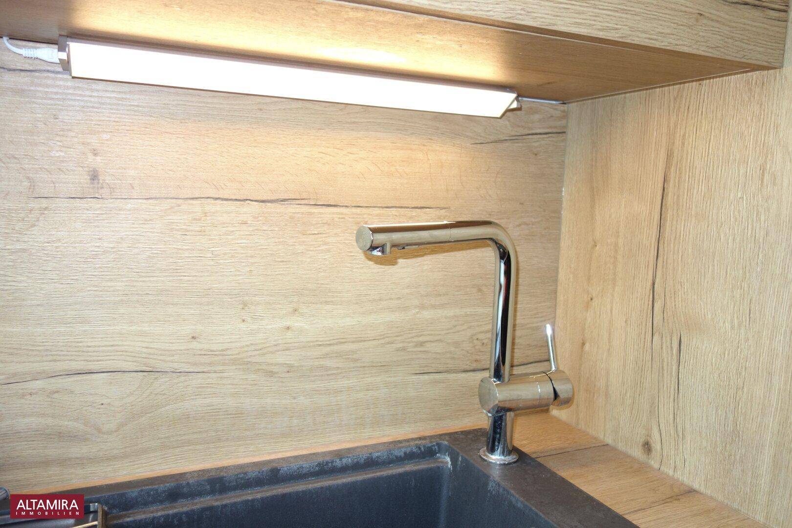 Nahaufnahme der Küchenspüle mit modernem Wasserhahn und praktischer Unterbauleuchte.