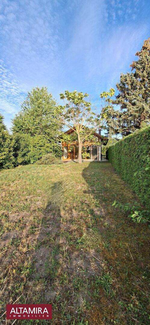 Weitläufiger Gartenbereich mit dem Haus im Hintergrund, umgeben von Bäumen und Grünflächen.