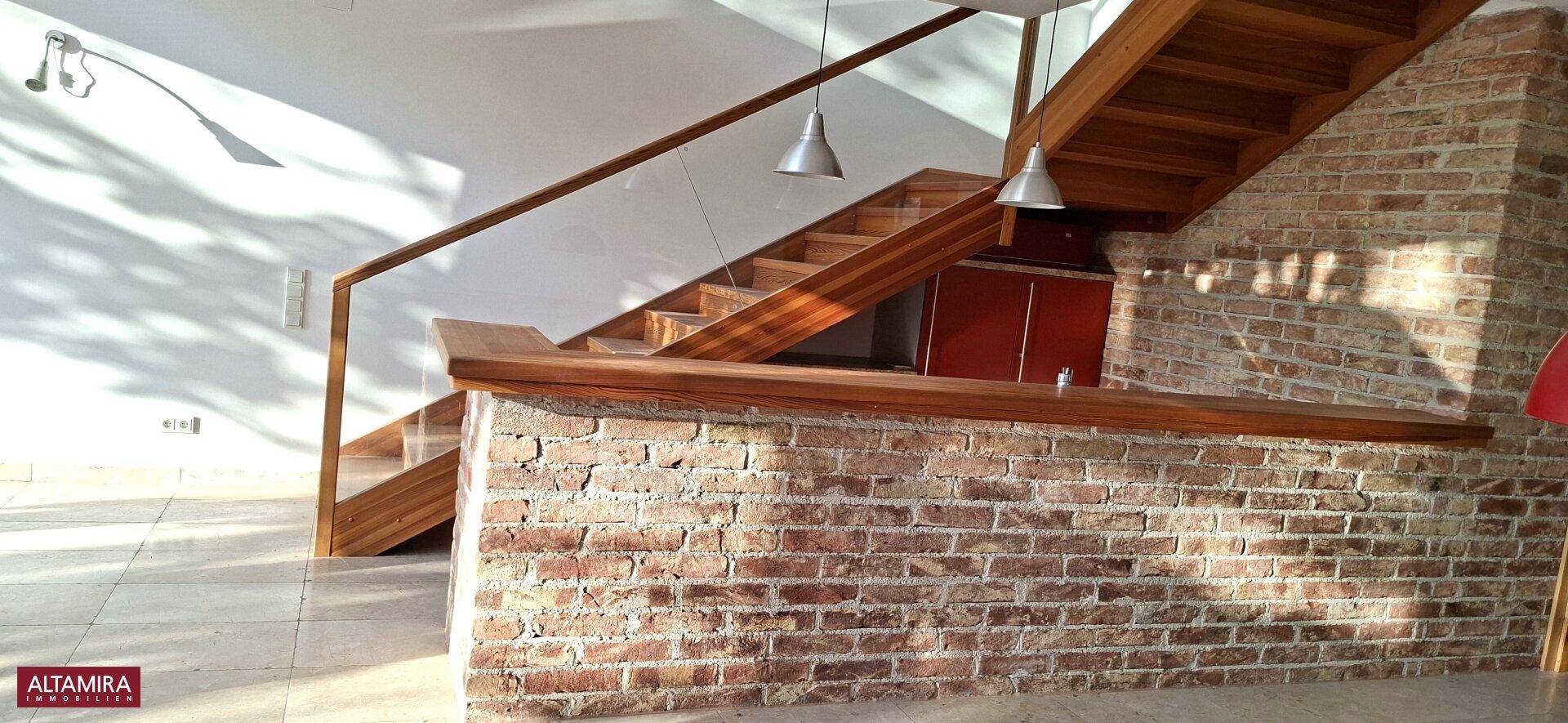 Detailansicht der eleganten Holztreppe und der rustikalen Ziegelbar im Wohnbereich.