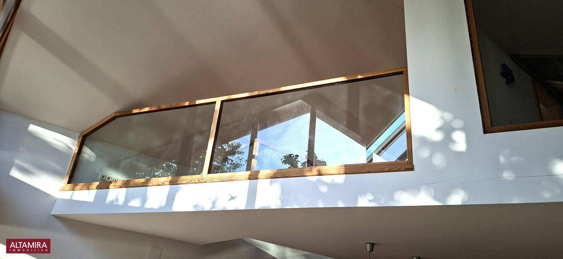 Obere Fensterfront mit Blick auf den Himmel und die Baumwipfel, die viel Licht hereinlässt.