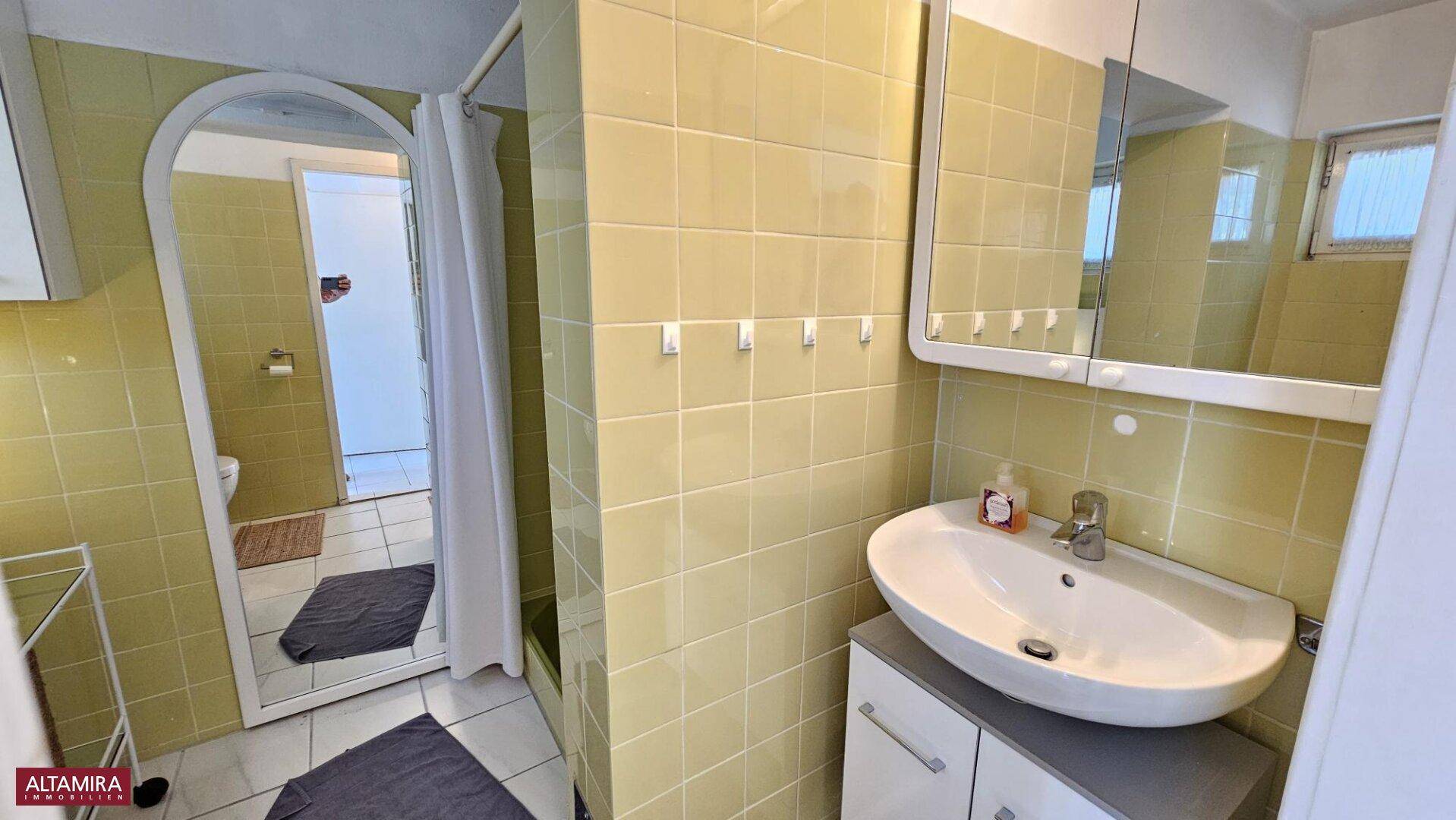 Badezimmer mit gelben Fliesen, modernem Waschbecken und einem Spiegel über dem Waschtisch.