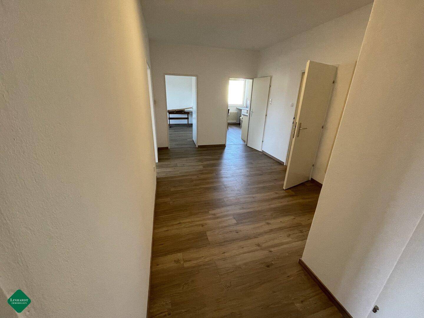 Heller Flur mit Laminatboden und Zugang zu mehreren Zimmern der Wohnung.