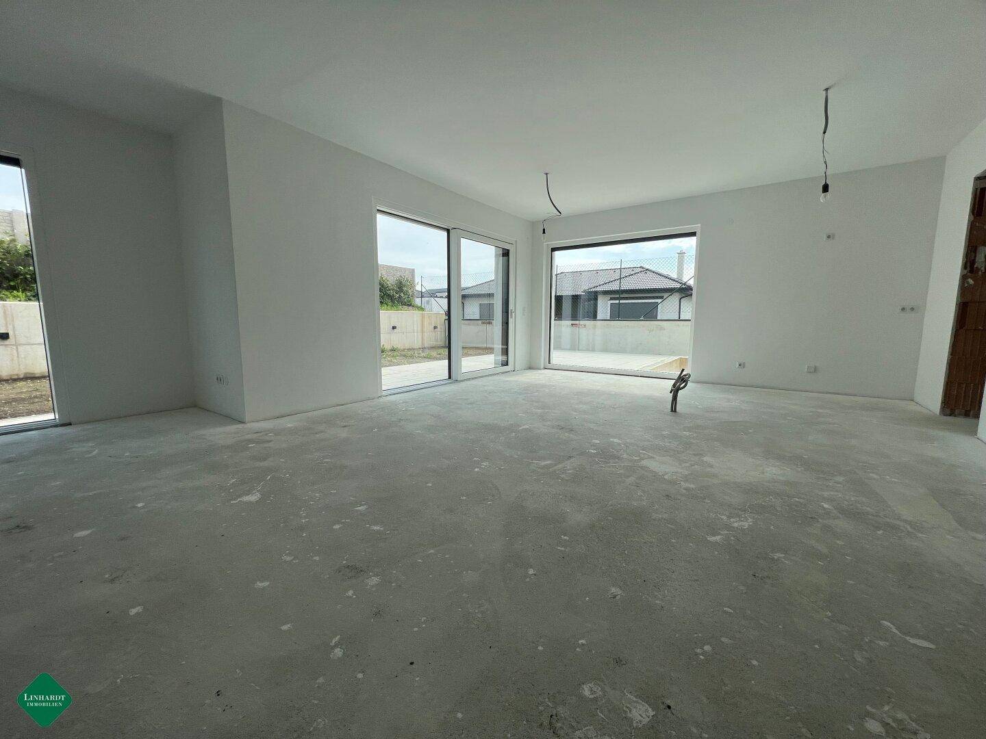 Helles, unfertiges Wohnzimmer mit großen Schiebetüren und Blick ins Grüne.