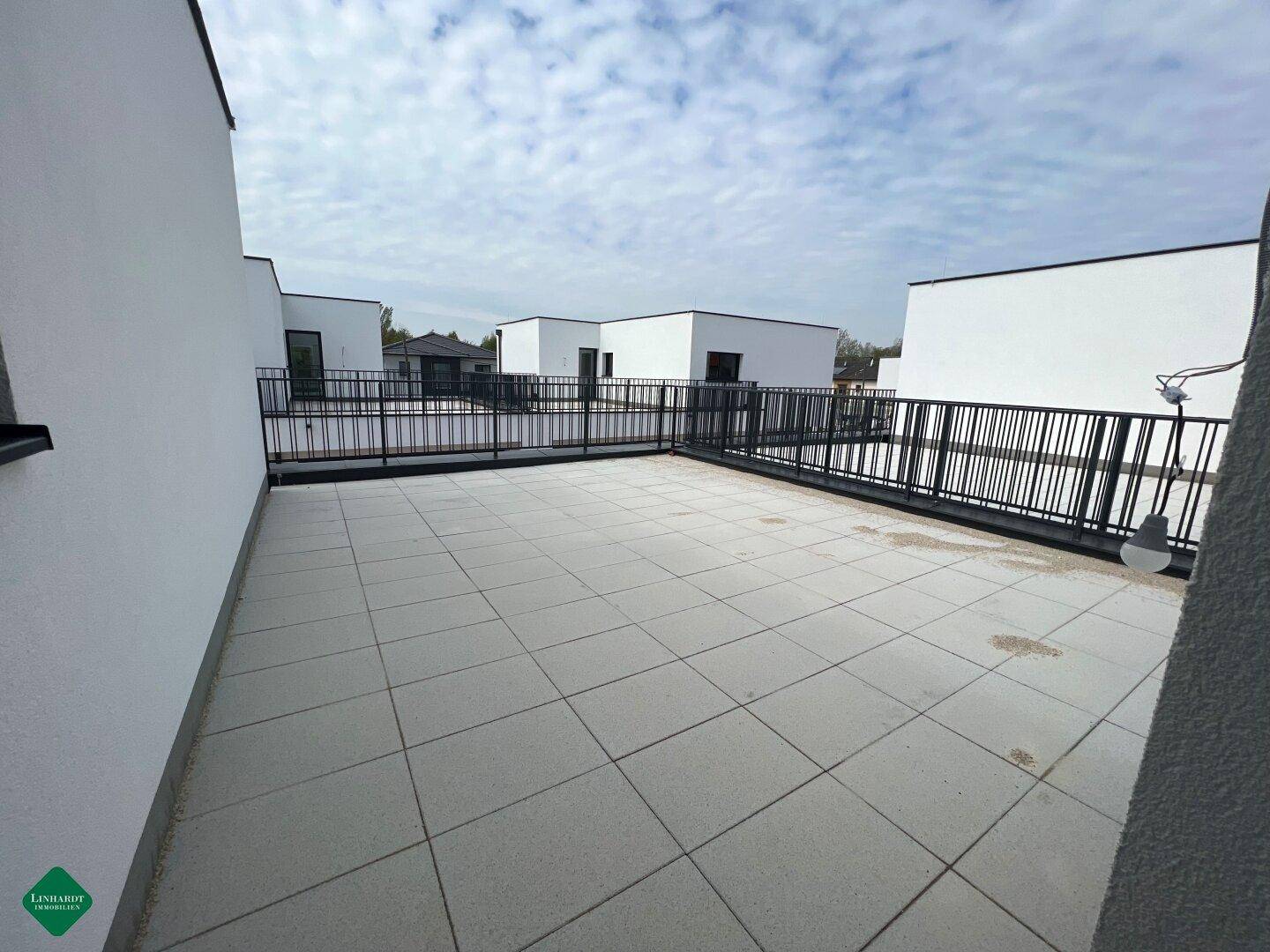 Geräumige Dachterrasse mit modernen Fliesen und Blick auf die umliegenden Neubauten.