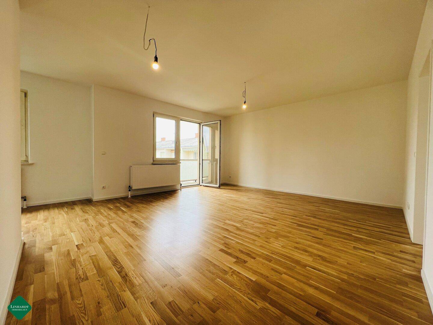 Geräumiges, helles Zimmer mit Parkettboden und direktem Zugang zu einem Balkon.