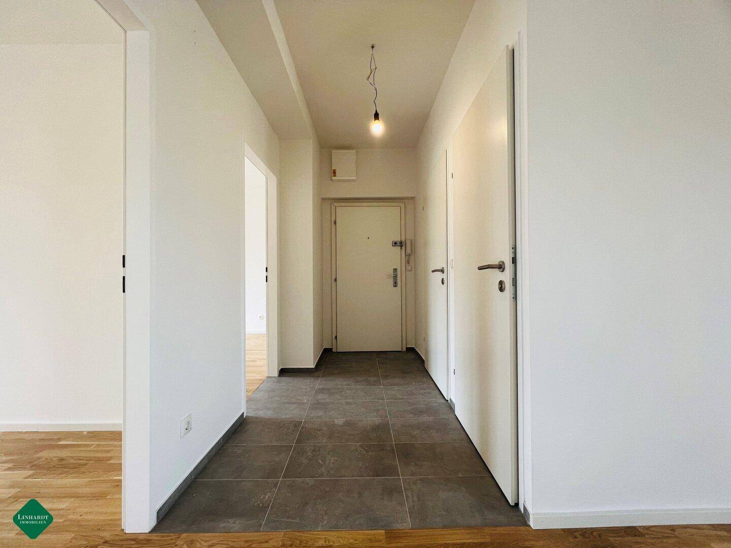 Heller Eingangsbereich mit Fliesenboden und Zugang zu verschiedenen Zimmern der Wohnung.