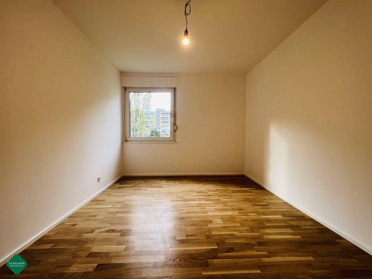 Helles Schlafzimmer mit Parkettboden und neutralen Wänden, bereit zur Einrichtung.