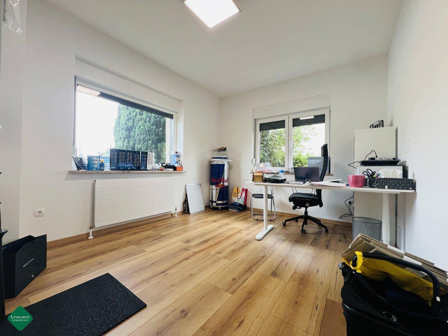 Funktionales Büro mit Holzboden und zwei großen Fenstern für viel Tageslicht.
