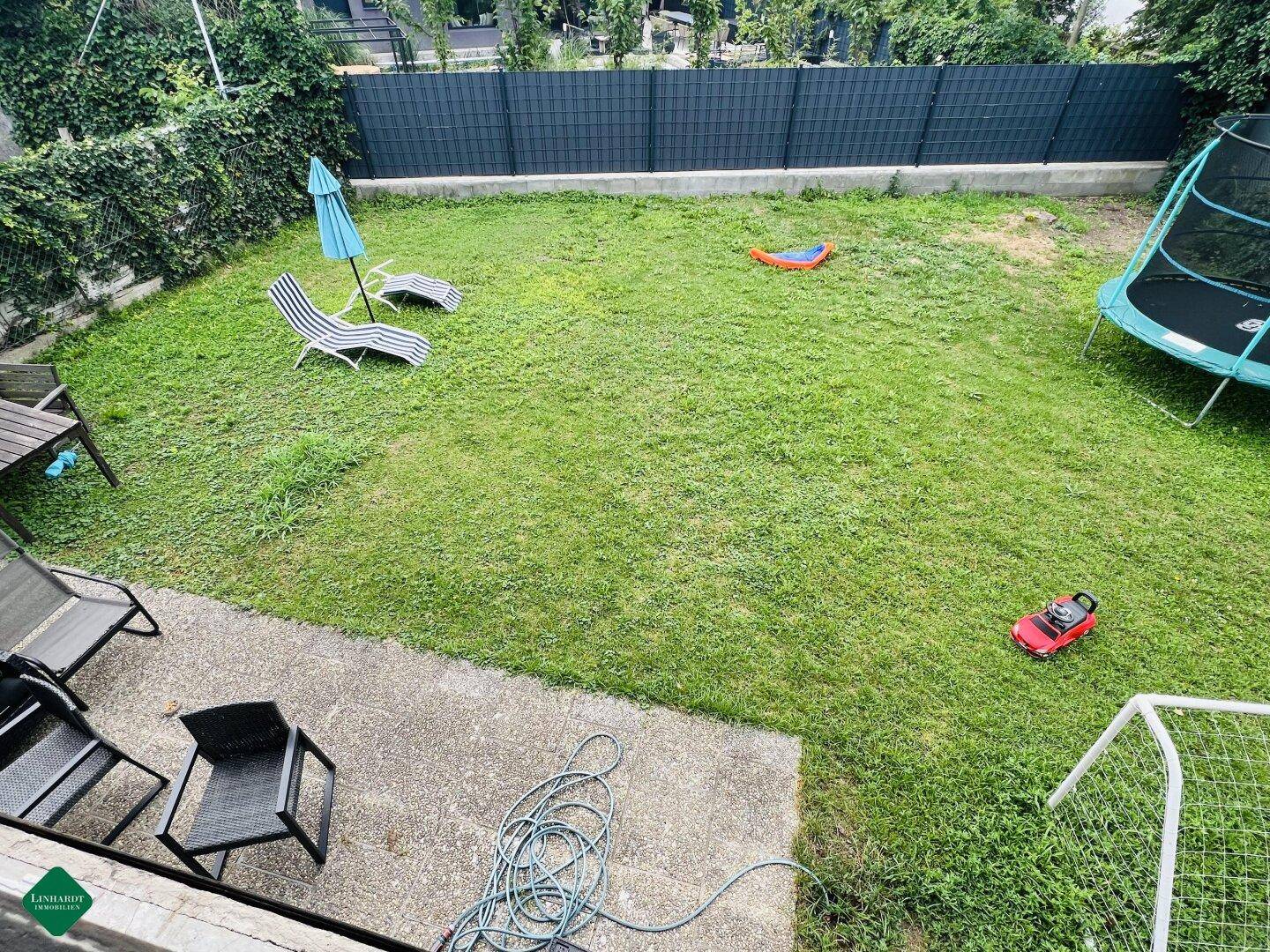 Großer, gepflegter Garten mit Rasenfläche, Trampolin und Sitzgelegenheiten.