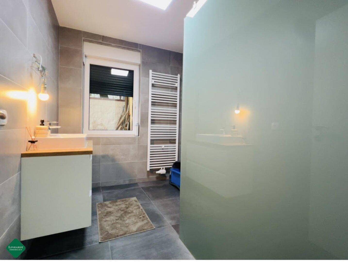Modernes Badezimmer mit Dusche, Fenster und beheiztem Handtuchhalter.