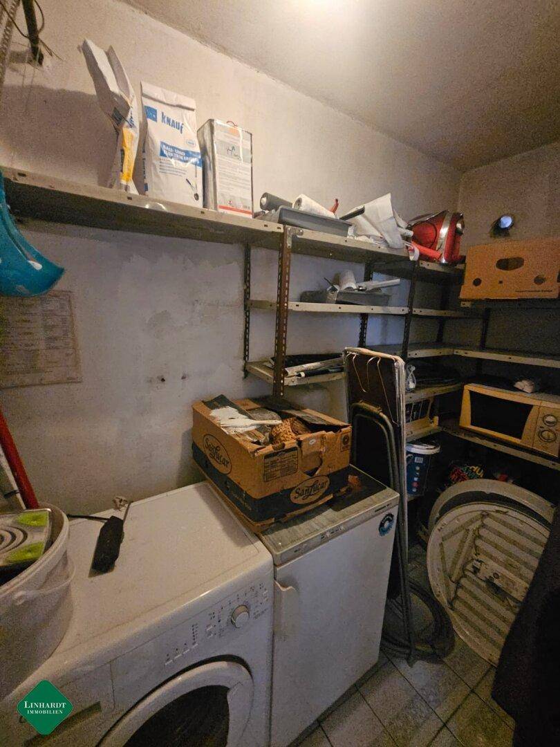Abstellraum mit Regalen, Waschmaschine und verschiedenen Haushaltsgegenständen für Lagerung.